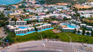An aerial view of a coastal resort with multiple hotel buildings, a large swimming pool, and a beach area. - Port Royal Villas & Spa (Rhodes)