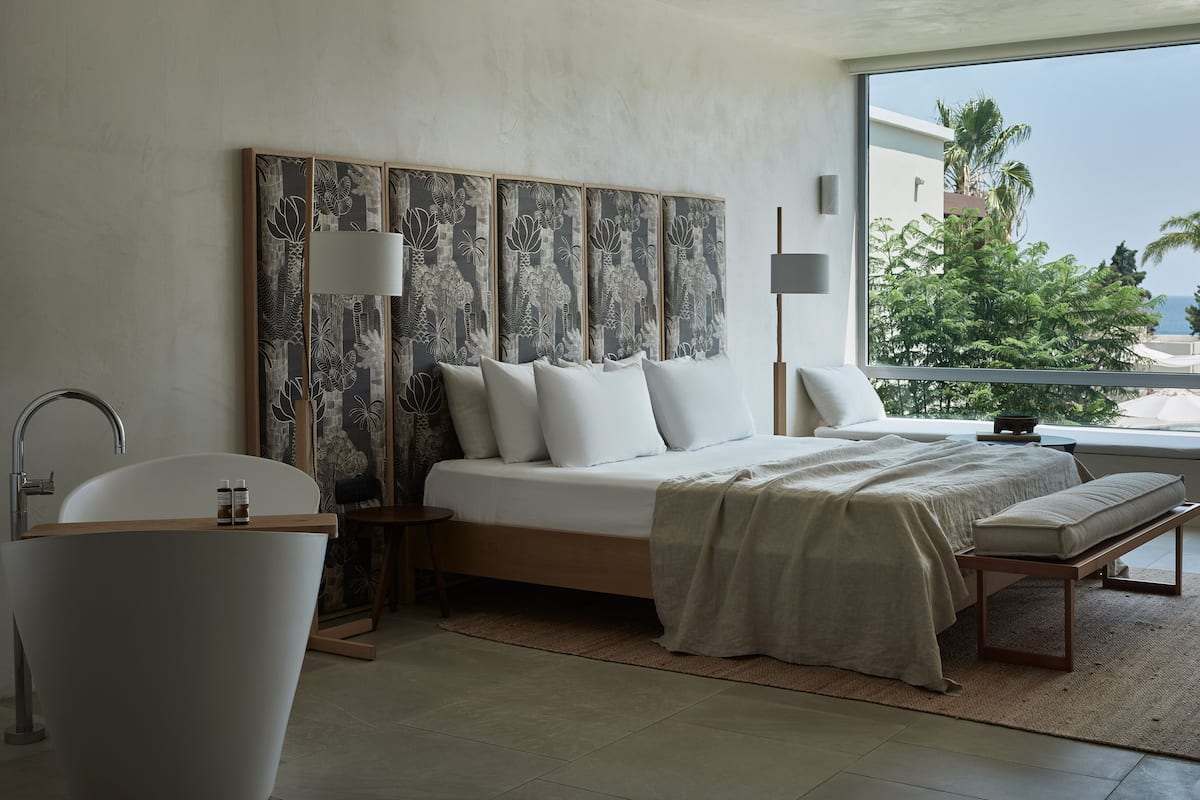 Une chambre moderne avec un grand lit, une baignoire et une vue sur des palmiers.