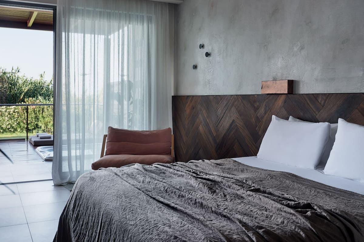 Une chambre moderne avec un grand lit, une vue sur la verdure et une porte-fenêtre coulissante.