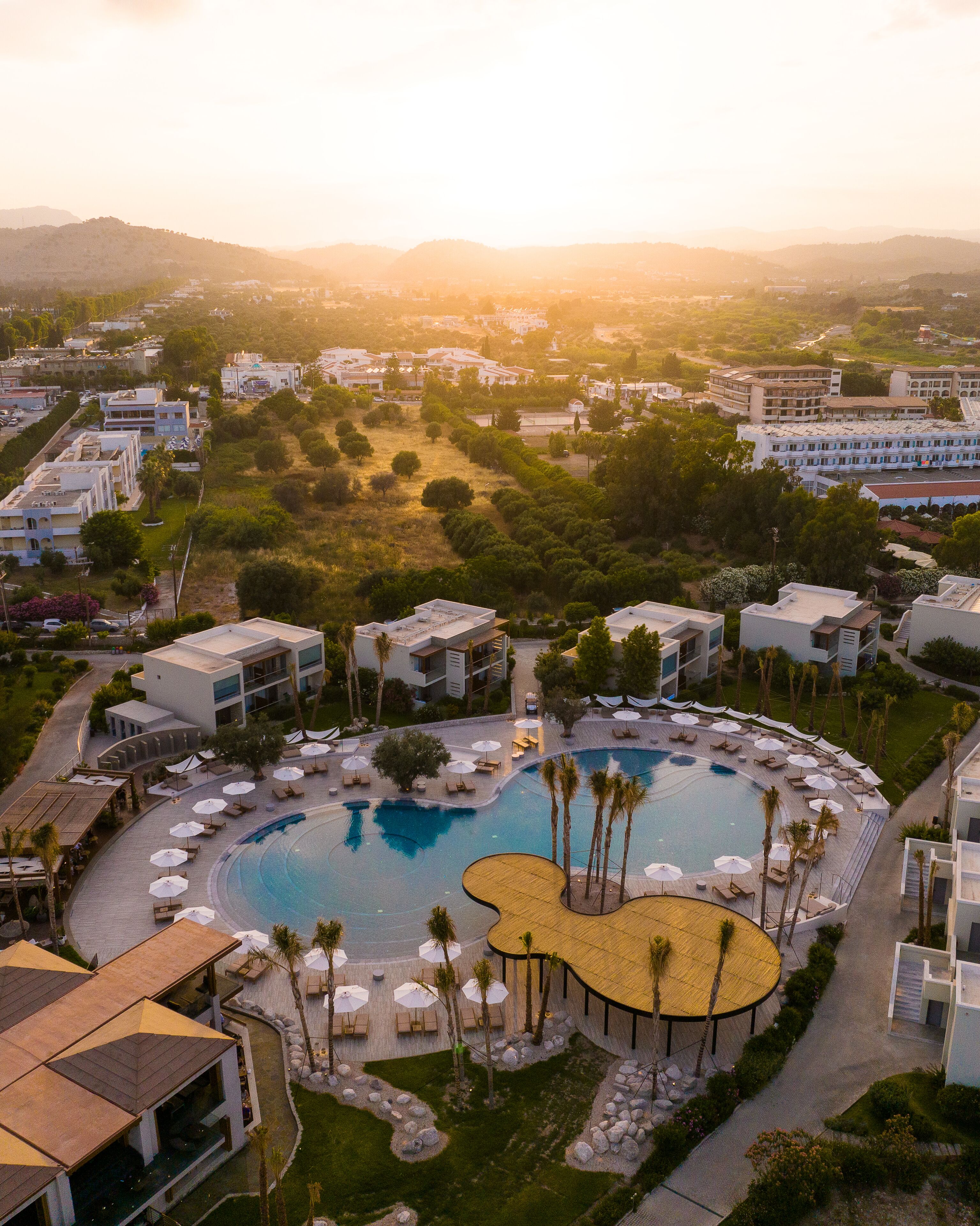 A resort with a central pool, multiple buildings, and surrounding greenery.