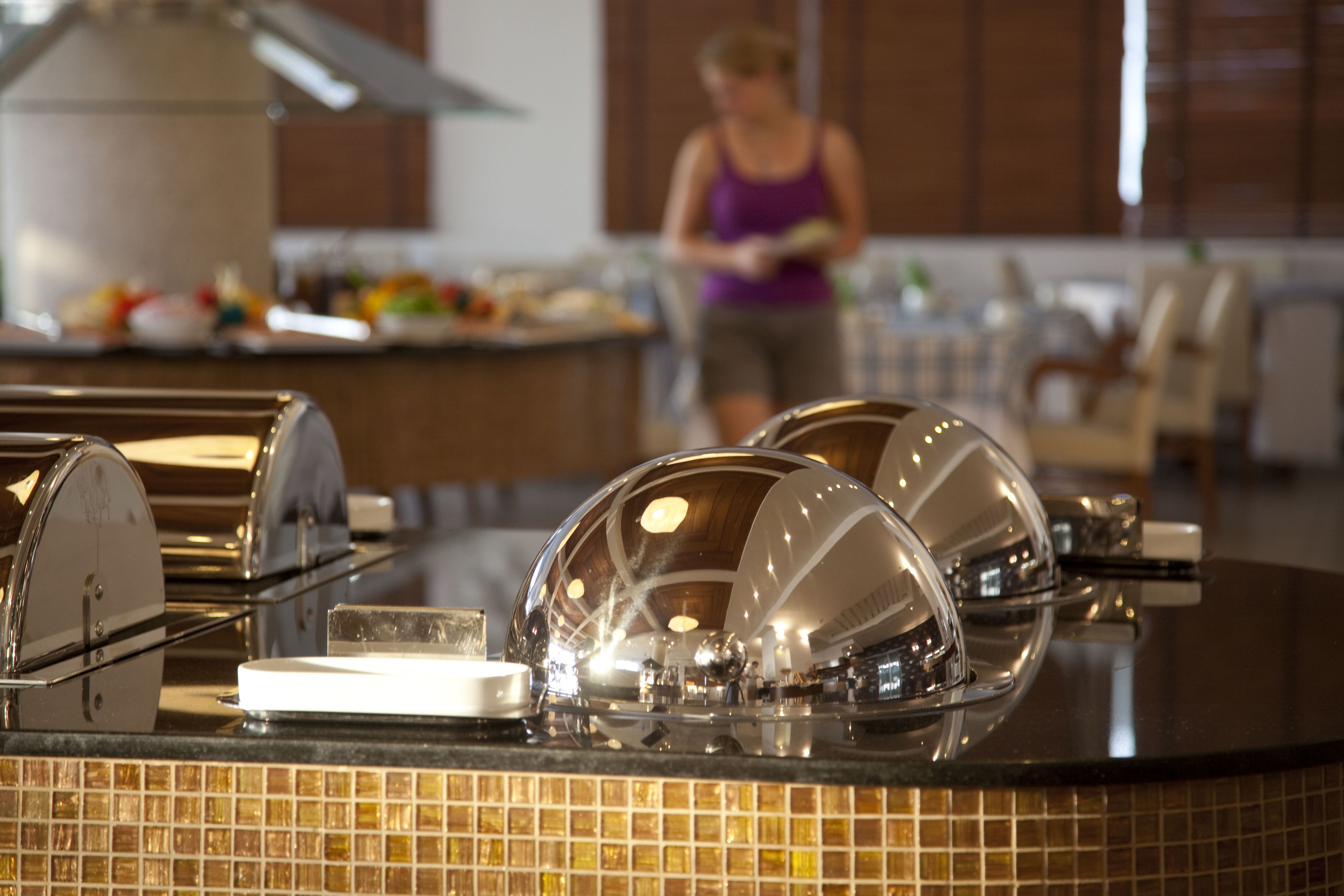 Una zona de cocina con un sistema tipo bufé, que incluye una presentación de alimentos y una persona al fondo.