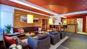 A modern lounge area with sofas, armchairs, and a bar area. - AlpenParks Hotel Maria Alm (Maria Alm am Steinernen Meer)