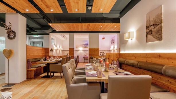 A restaurant with wooden flooring, a long dining table, and booths. - AlpenParks Hotel Maria Alm (Maria Alm am Steinernen Meer)