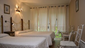 Een slaapkamer met twee bedden, een nachtkastje, een stoel en een raam met gordijnen.
