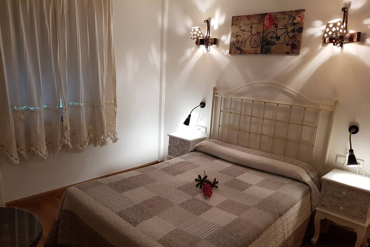 Ein ordentlich eingerichtetes Schlafzimmer mit Bett, Nachttischen und Wandlampen.