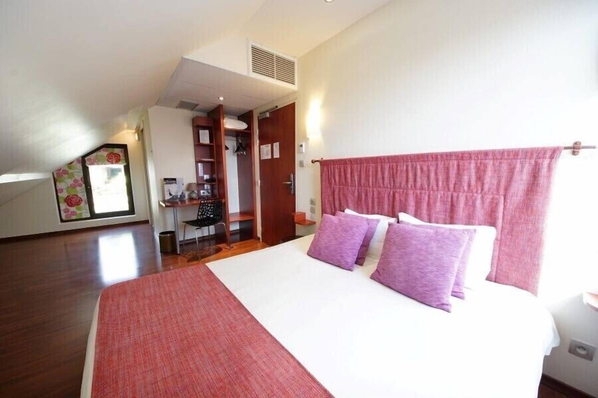 A bedroom with a large bed, a wardrobe, a desk, and a closet.