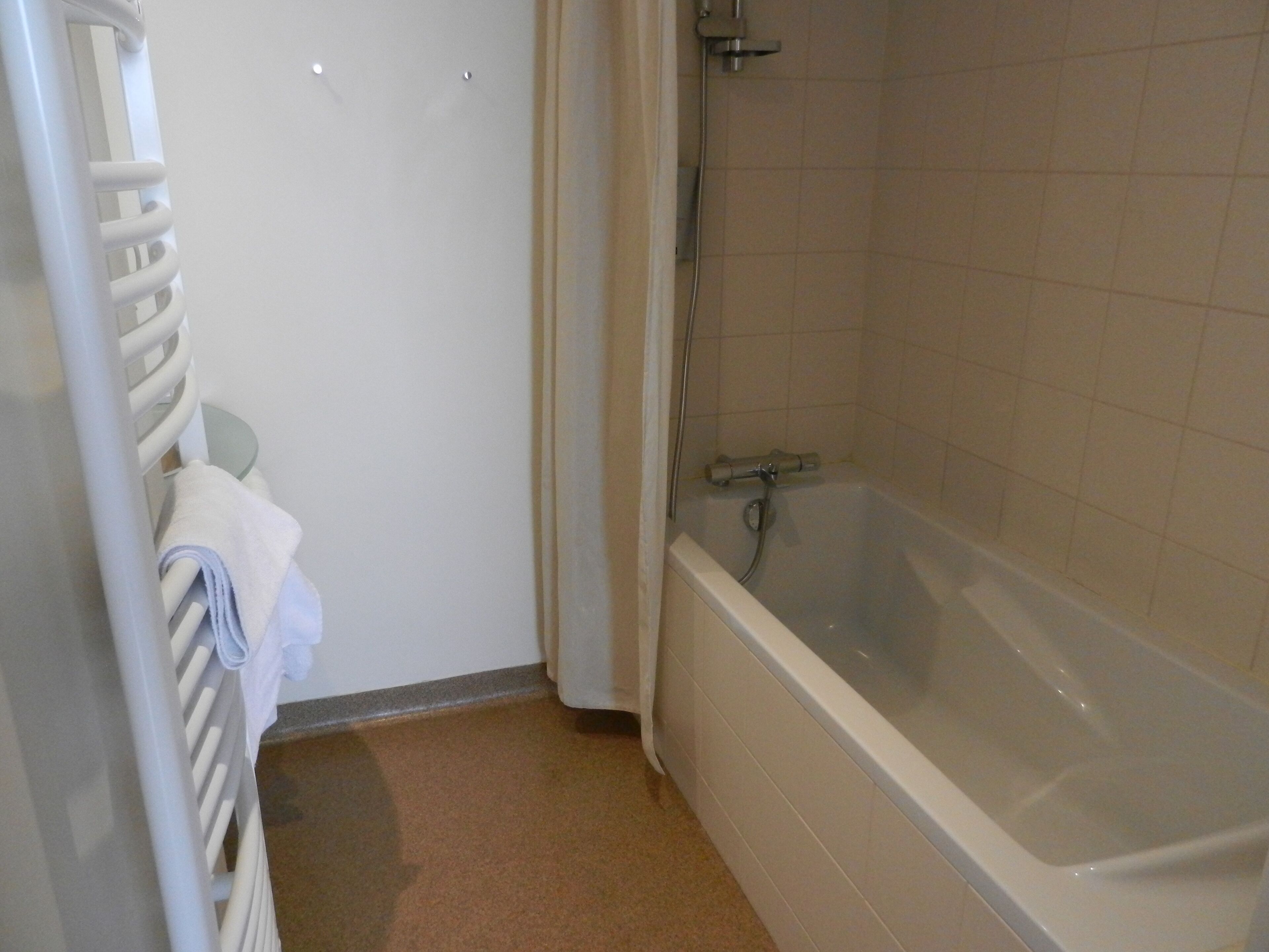 Un baño con bañera, perchero y ducha.