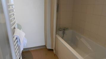 A bathroom with a bathtub, a towel rack, and a shower.