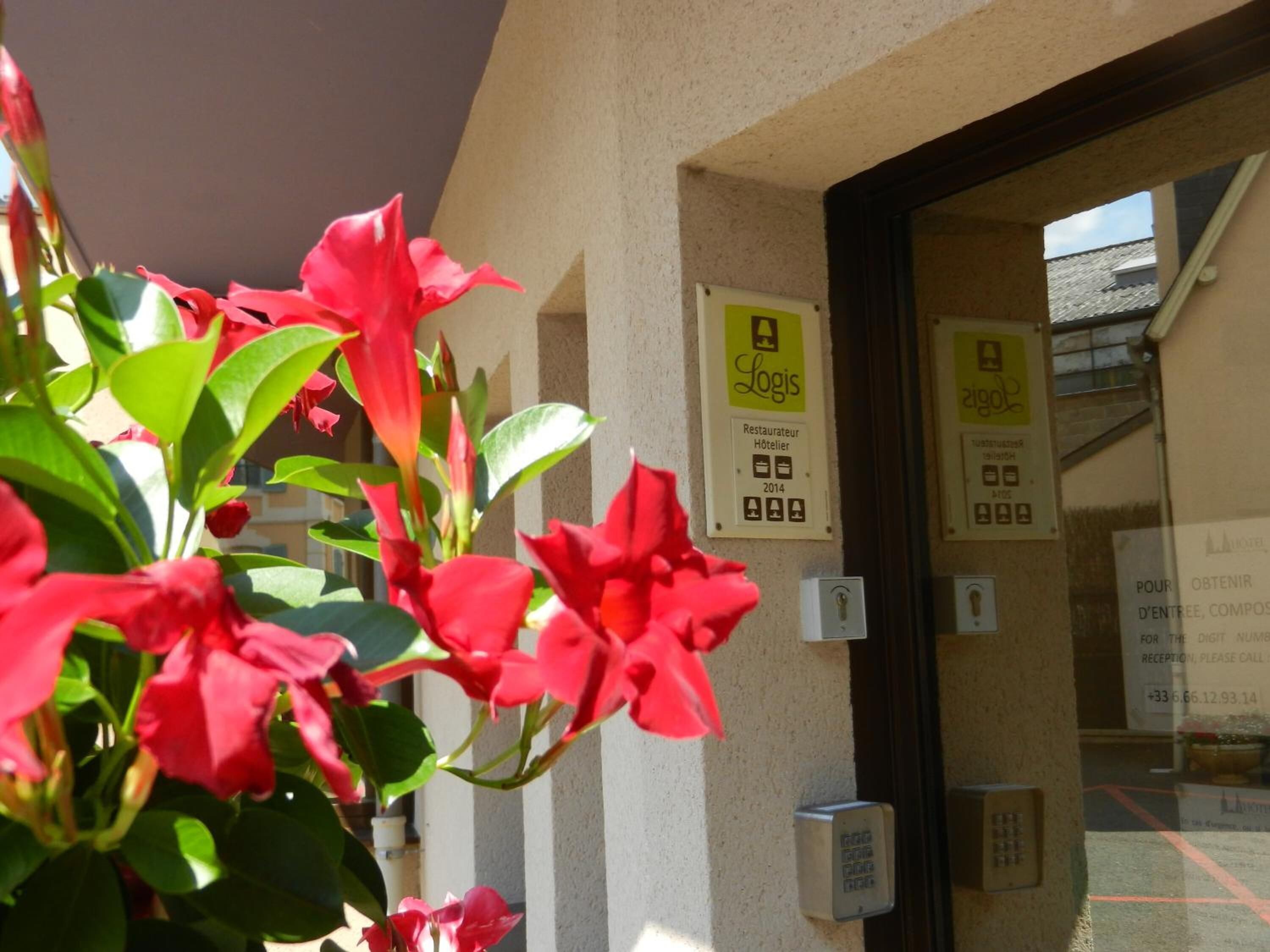 A hotel entrance with a reception desk, a sign indicating 'Logis' and 'Hôtelier 2014', and a security intercom.