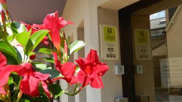 A hotel entrance with a reception desk, a sign indicating 'Logis' and 'Hôtelier 2014', and a security intercom.