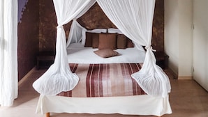 A four-poster canopy bed with a striped rug, pillows, and a wooden floor. - L'Hôtel (Chartres)