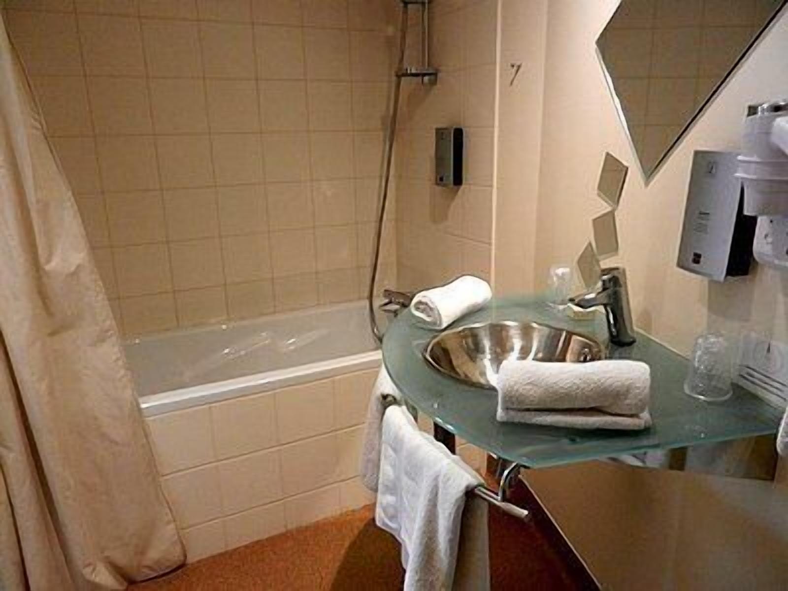 Ein Badezimmer mit einem Waschbecken aus Glas, einem Spiegel, einem Handtuchhalter und einer Dusche.