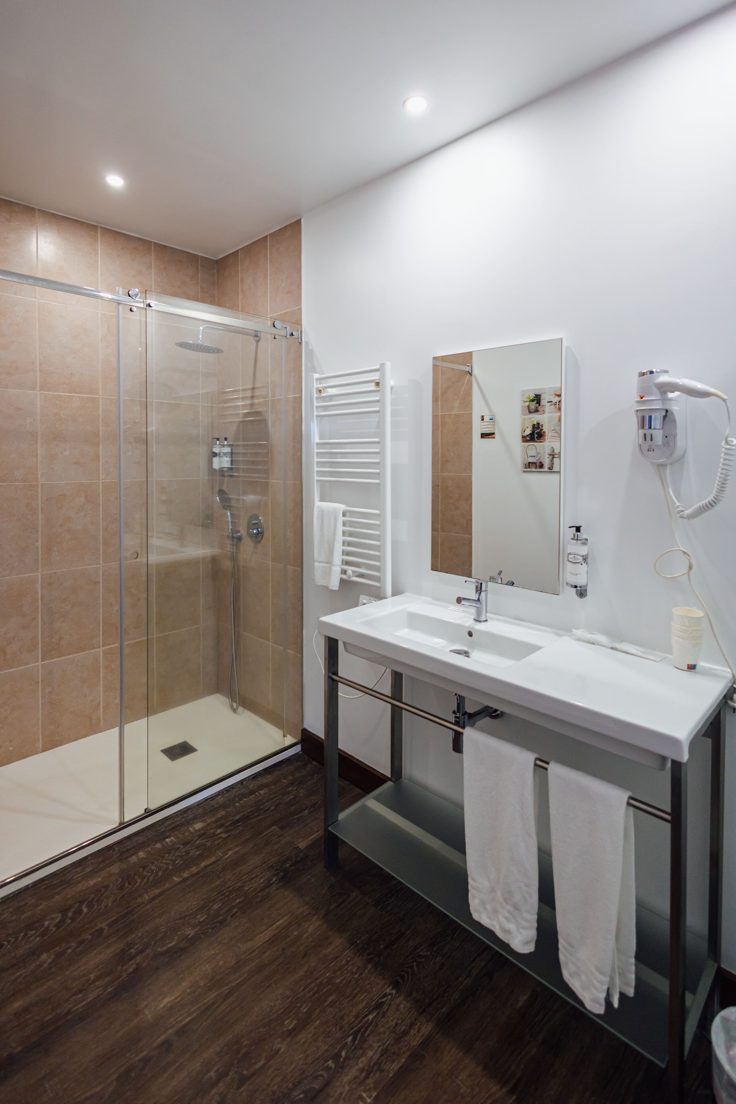 Une salle de bain moderne avec une douche à parois de verre, un lavabo blanc et un miroir.