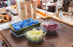 A buffet table with various food items including yogurt, diced potatoes, and grapes.