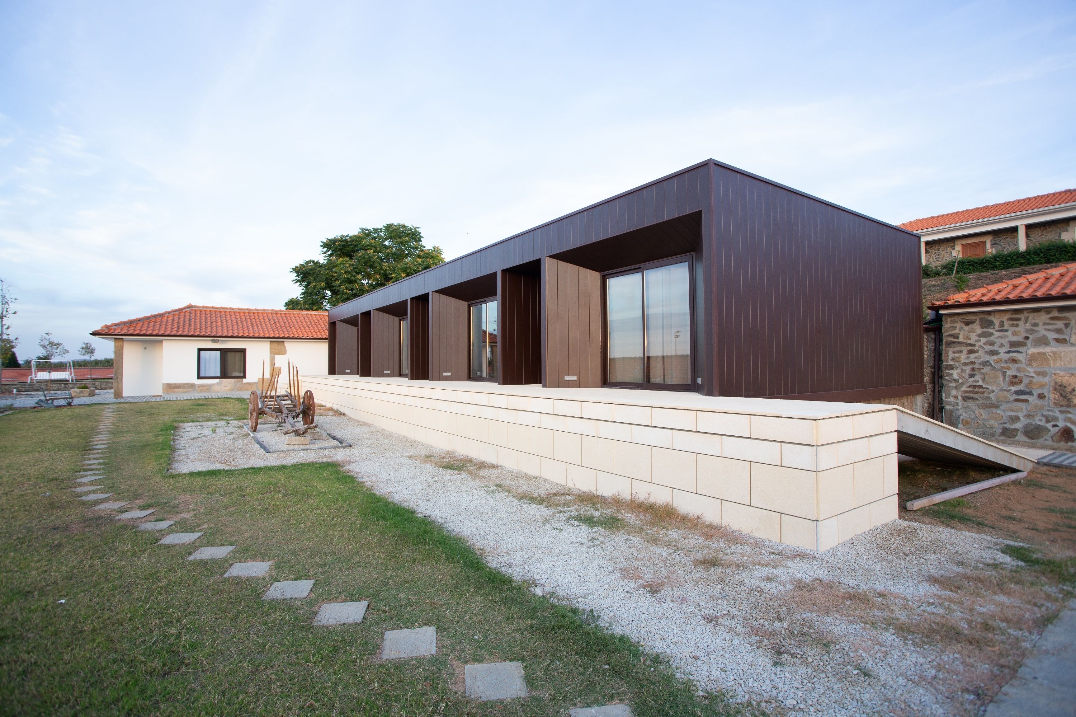 A modern building with a flat roof, large windows, and a paved entrance area.