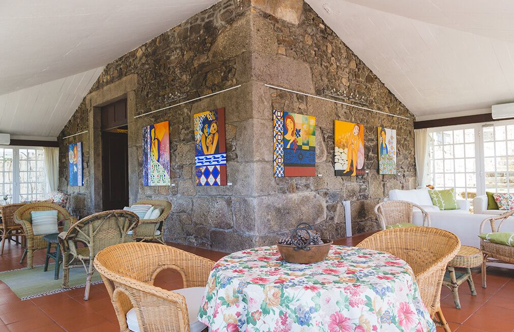 A stone-walled room with wicker furniture and a floral tablecloth.