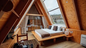 A cozy, triangular wooden cabin with a bed, a small table, and a shower area. - Quinta da Barroca (Armamar)