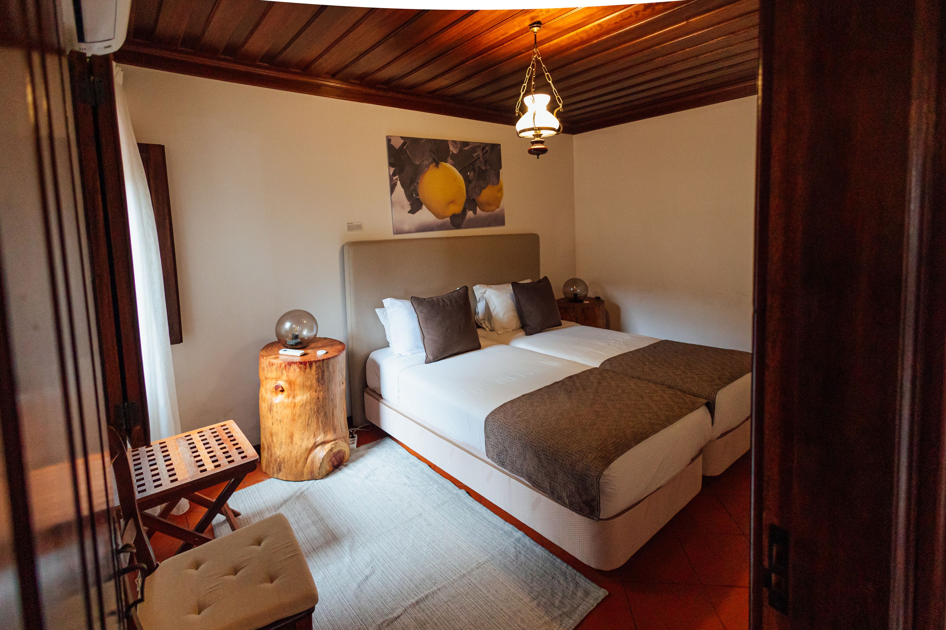 Un dormitorio con una cama grande, una mesita de noche de madera, una pequeña mesa y una lámpara colgante.