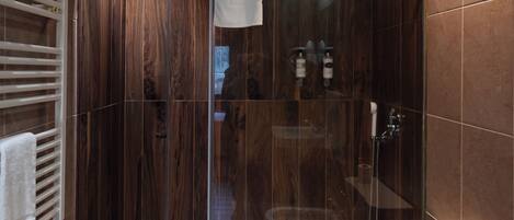 A modern bathroom with a glass-enclosed shower, a toilet, and a towel rack.