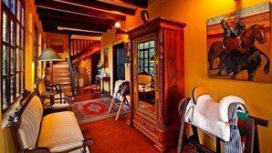 A cozy room with a wooden bench, a mirror, a horse saddle, and a painting of a horse. - Hacienda Hato Verde (Latacunga)