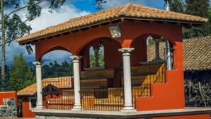 A red-roofed building with stone columns, a balcony, and a chimney. - Hacienda Hato Verde (Latacunga)