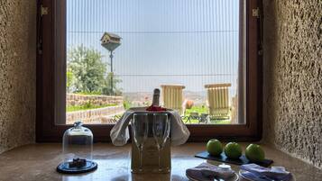 Una mesa con una botella de champán, dos copas, un vaso de agua y tres manzanas verdes sobre una encimera de piedra.