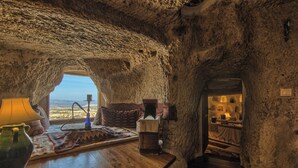 Un interior rústico con una pared de piedra, una zona de bar de madera con una lámpara y vistas a través de una ventana.