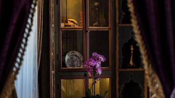 A room with a wooden cabinet containing a clock, a vase with flowers, and decorative items.