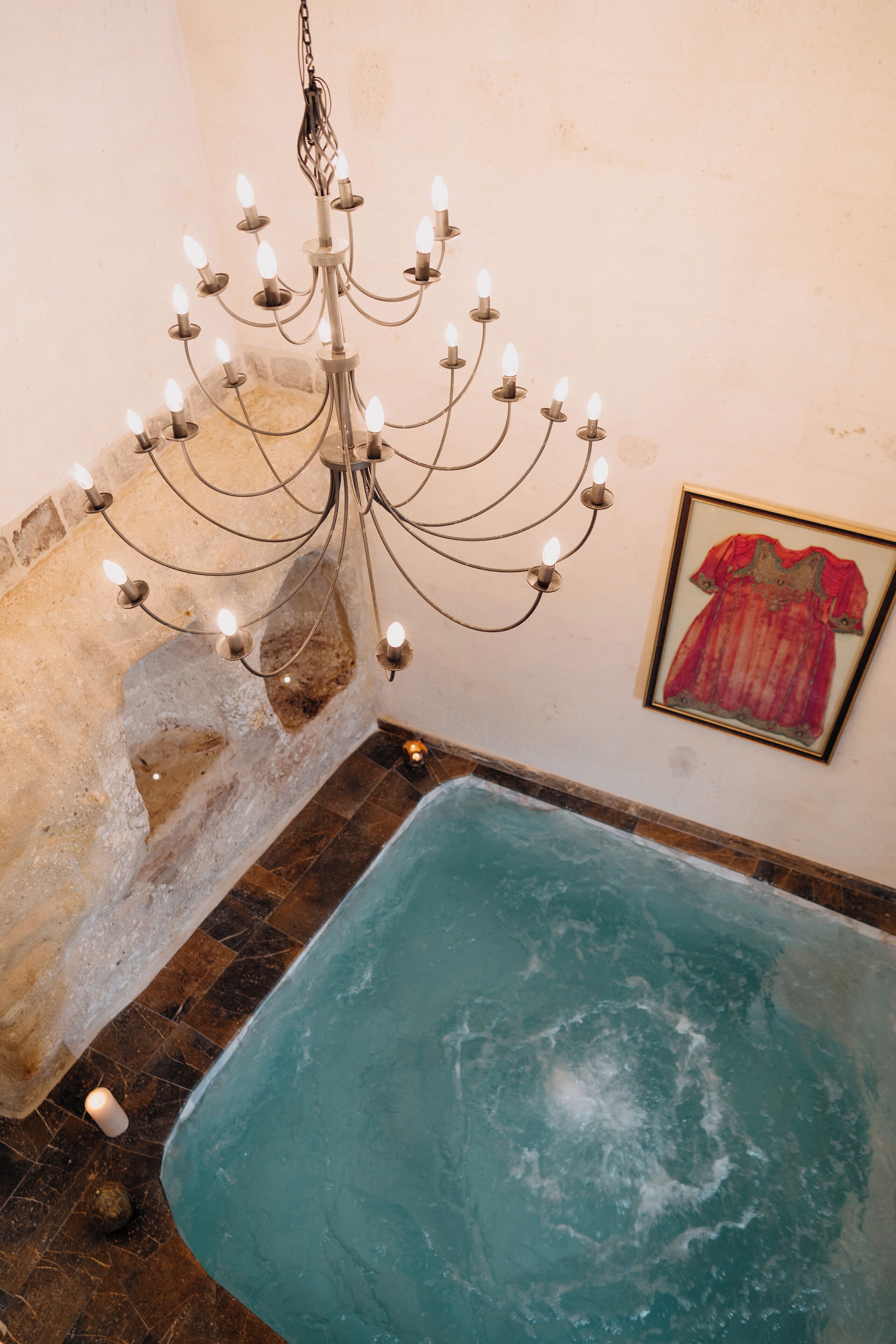 Una stanza con una grande vasca da bagno, un lampadario e un quadro appeso al muro.