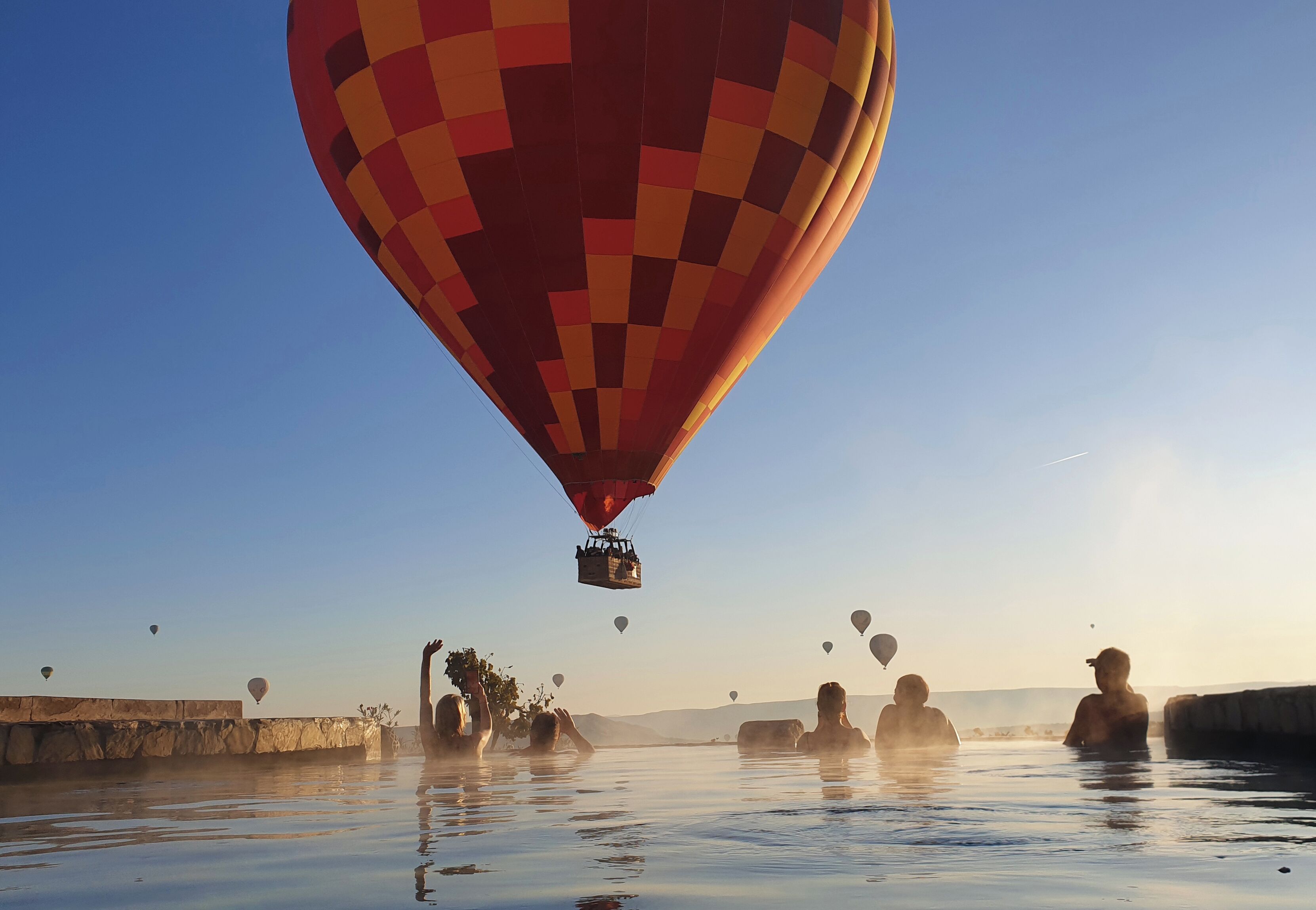 Un globo aerostático flotando sobre una masa de agua, con gente en el agua debajo.