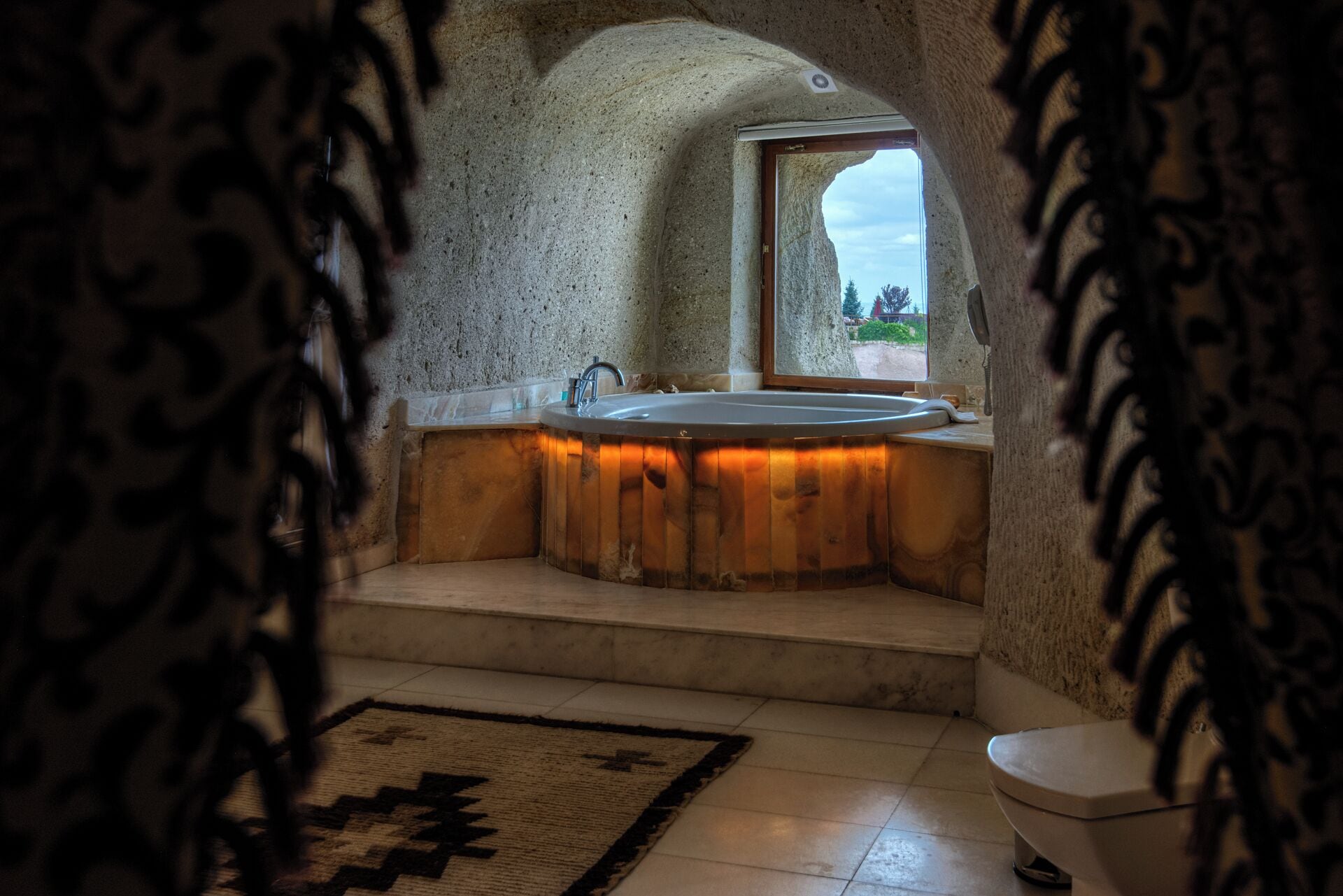 A bathroom with a freestanding bathtub, a window, and a toilet.