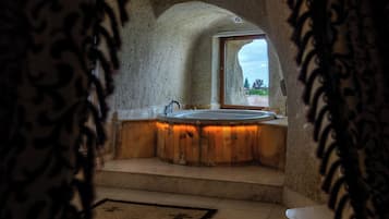 A bathroom with a freestanding bathtub, a window, and a toilet.