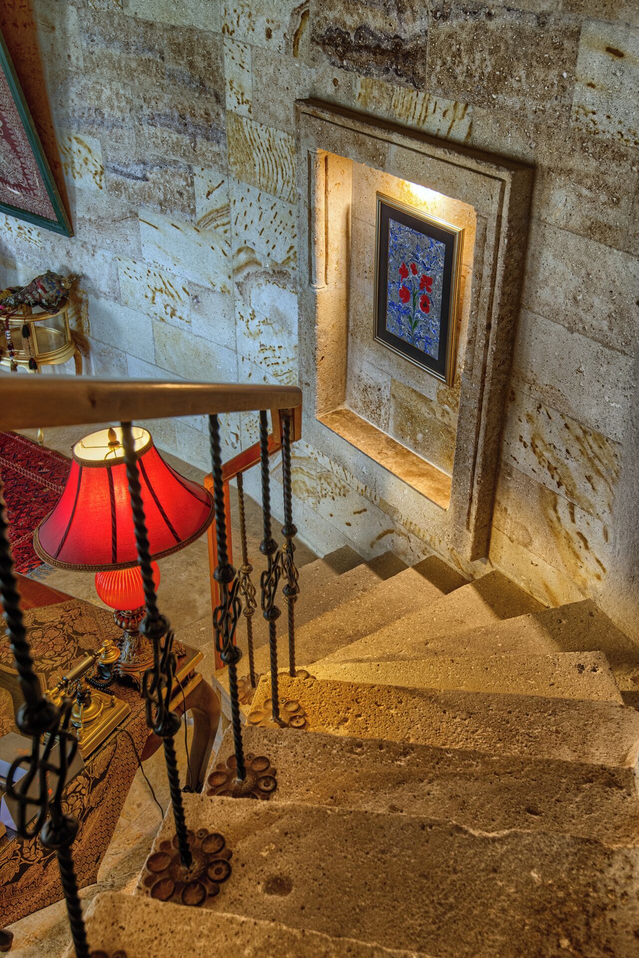A staircase with a red lamp, a framed picture, and a patterned rug.