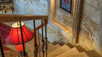 A staircase with a red lamp, a framed picture, and a patterned rug.
