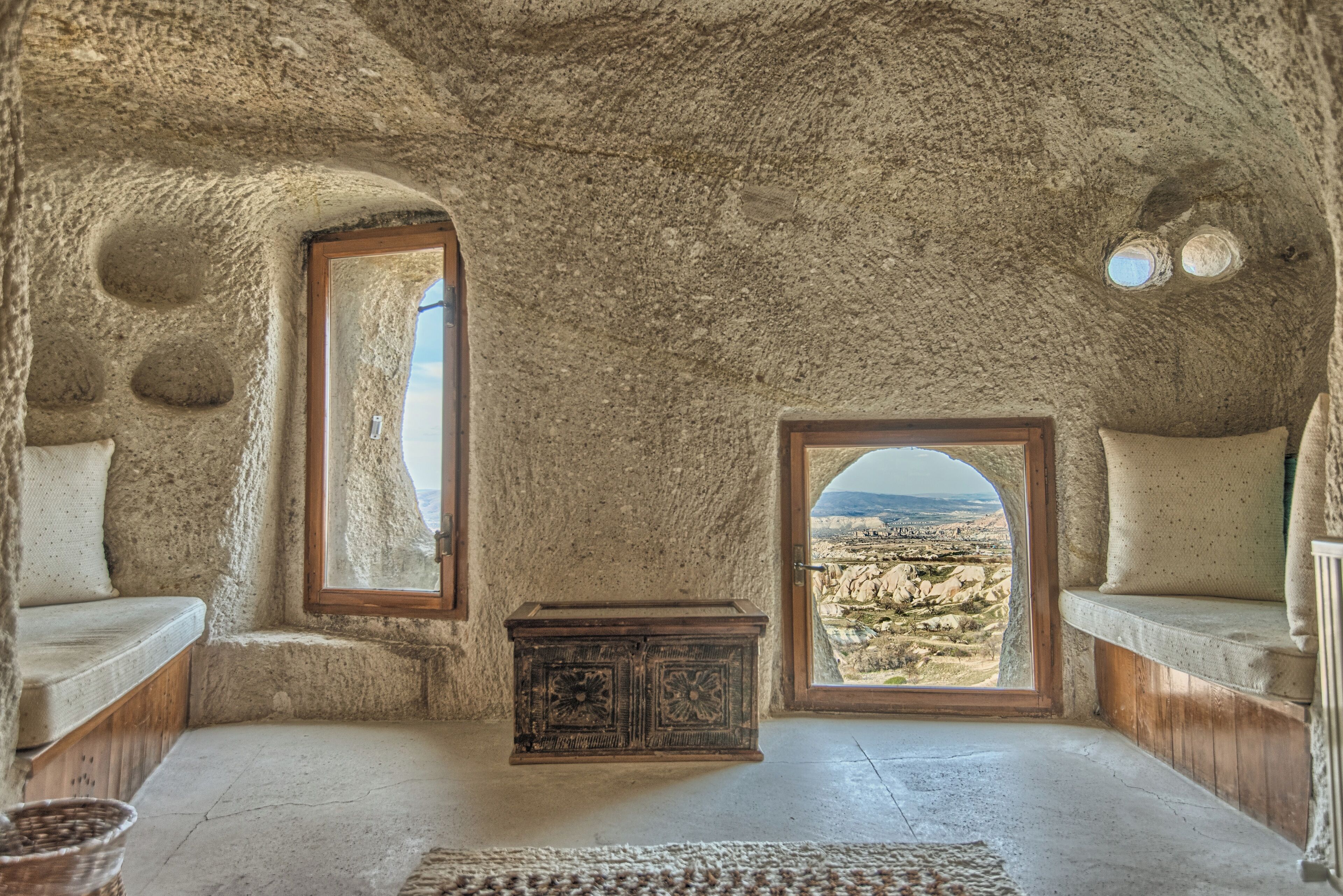 A room with a stone ceiling, a wooden cabinet, and a view of a rocky landscape through a window.