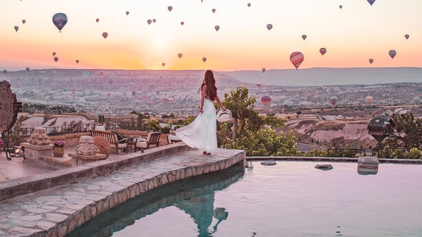 Zona de piscina con vistas a globos aerostáticos al atardecer.