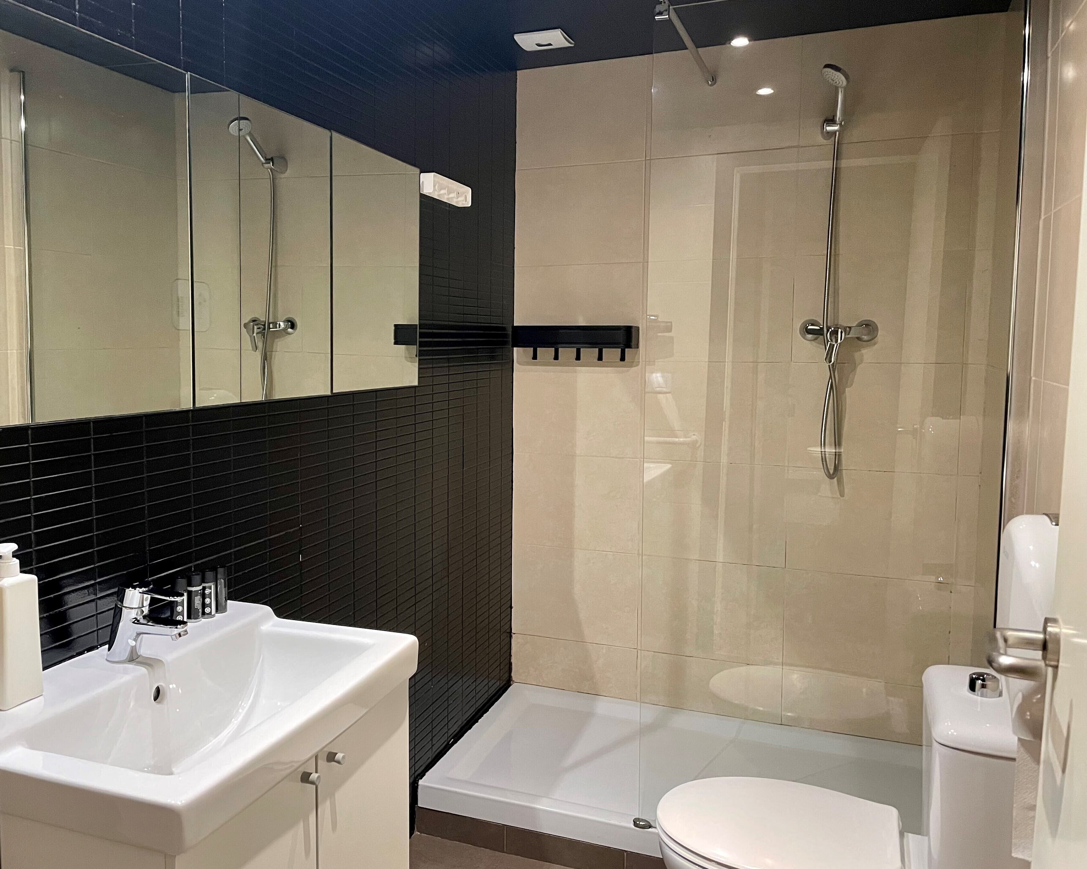 Un baño moderno con lavamanos, espejo y retrete blancos.