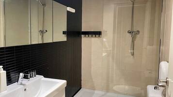 Un baño moderno con lavamanos, espejo y retrete blancos.
