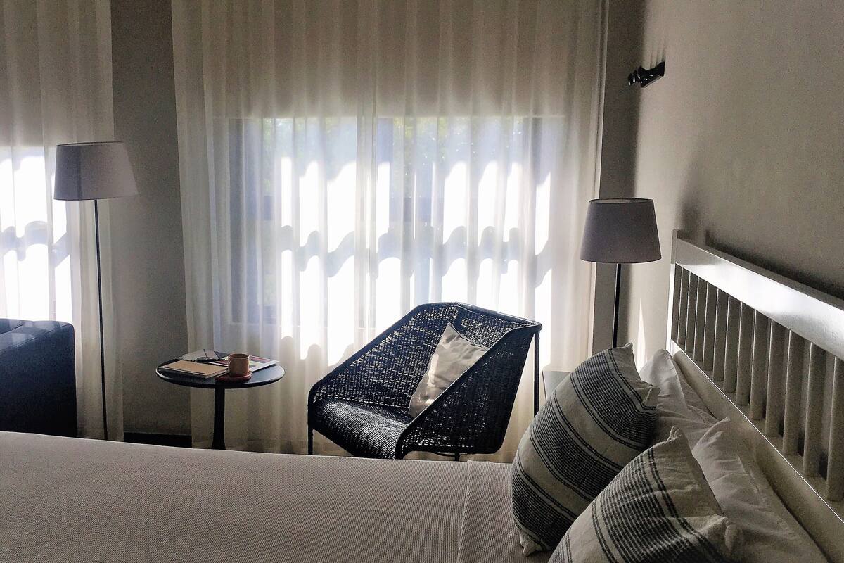 Una habitación de hotel con una cama, una silla, una mesita y una lámpara.