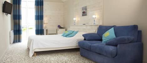 Ein Schlafzimmer mit einem Bett, einem blauen Sofa, einem an der Wand befestigten Fernseher und einer Holzwand.