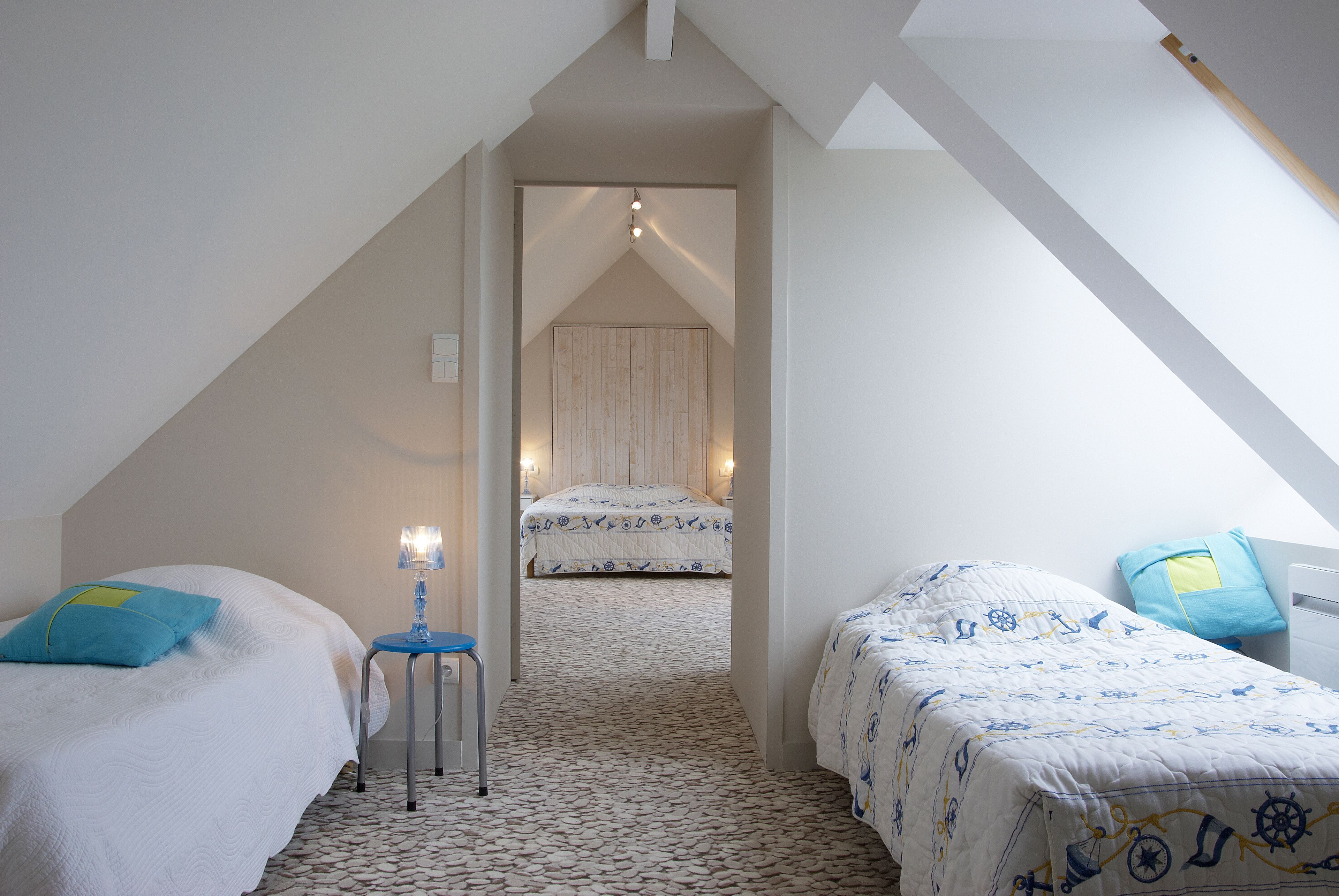 Een slaapkamer met twee bedden, een klein tafeltje en een lamp.