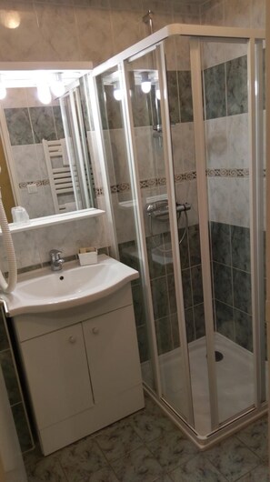 A bathroom with a glass-enclosed shower, a white sink, and a mirror above the sink. - Logis de L'Europe (Corbigny)