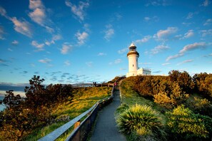 A lighthouse on a grassy hill with a pathway leading to it.