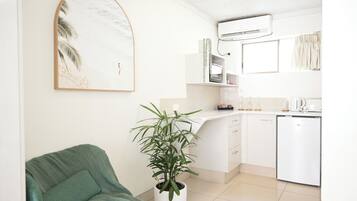 Una cocina moderna con armarios blancos, lavavajillas integrado y una planta en maceta.