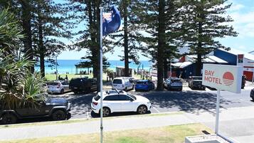 Un'area di parcheggio con un cartello del 'Bay Motel', un'asta con una bandiera e vista sull'oceano.