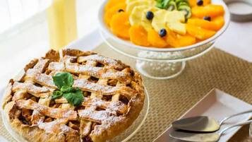 Ein Kuchen mit Gitterteig und eine Obstschale mit geschnittenem Obst und Blaubeeren.