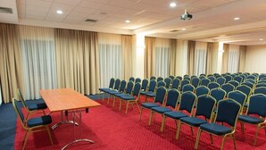 A conference room with a long table and rows of chairs, red carpet, and beige curtains. - Business Hotel Vega (Wroclaw)