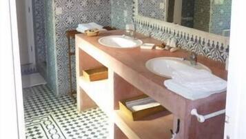 A bathroom with two sinks, a large mirror, patterned tiles, and a checkered floor.