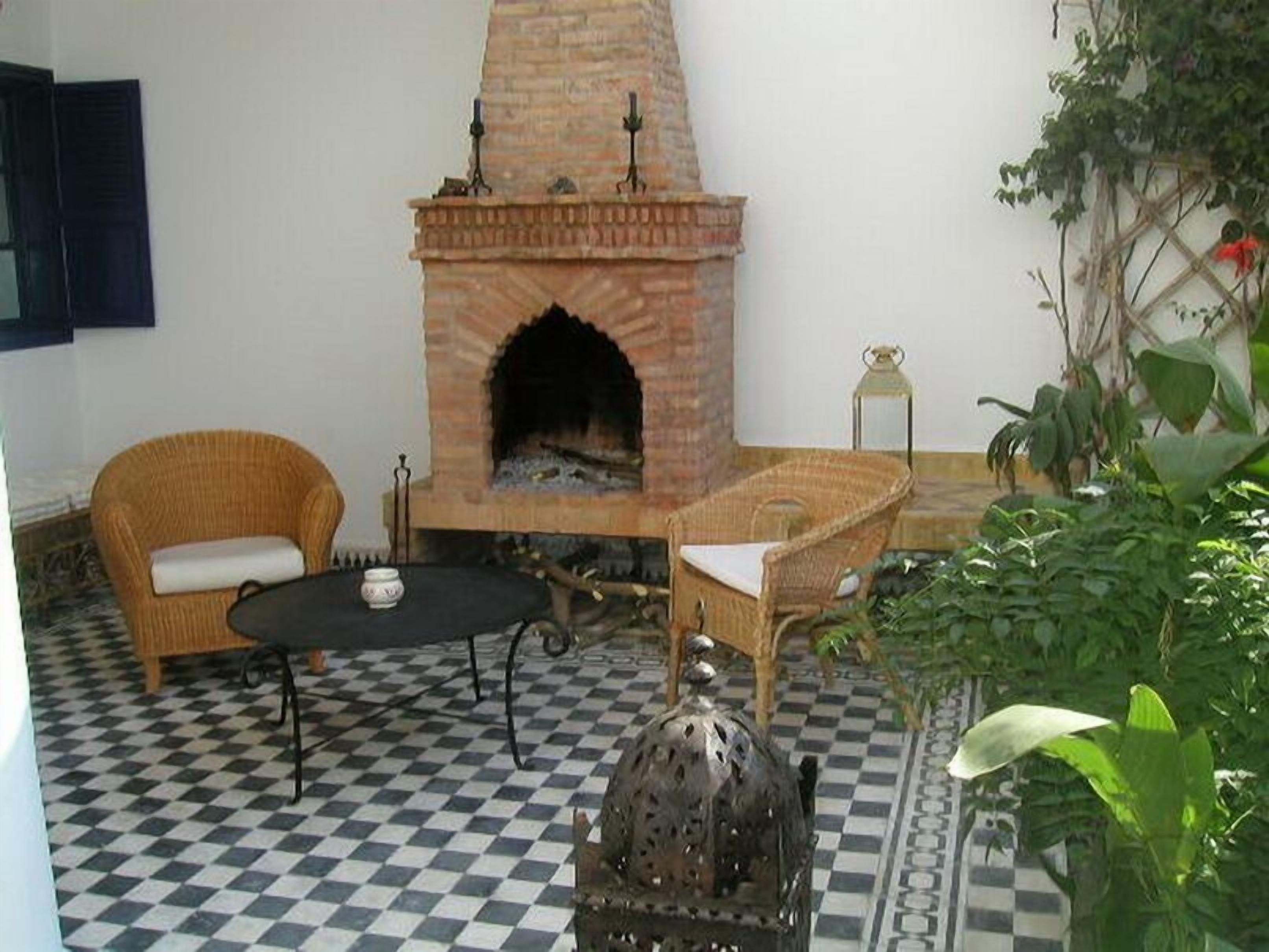 Un patio acogedor con suelo a cuadros, mobiliario de mimbre y una chimenea de ladrillo.