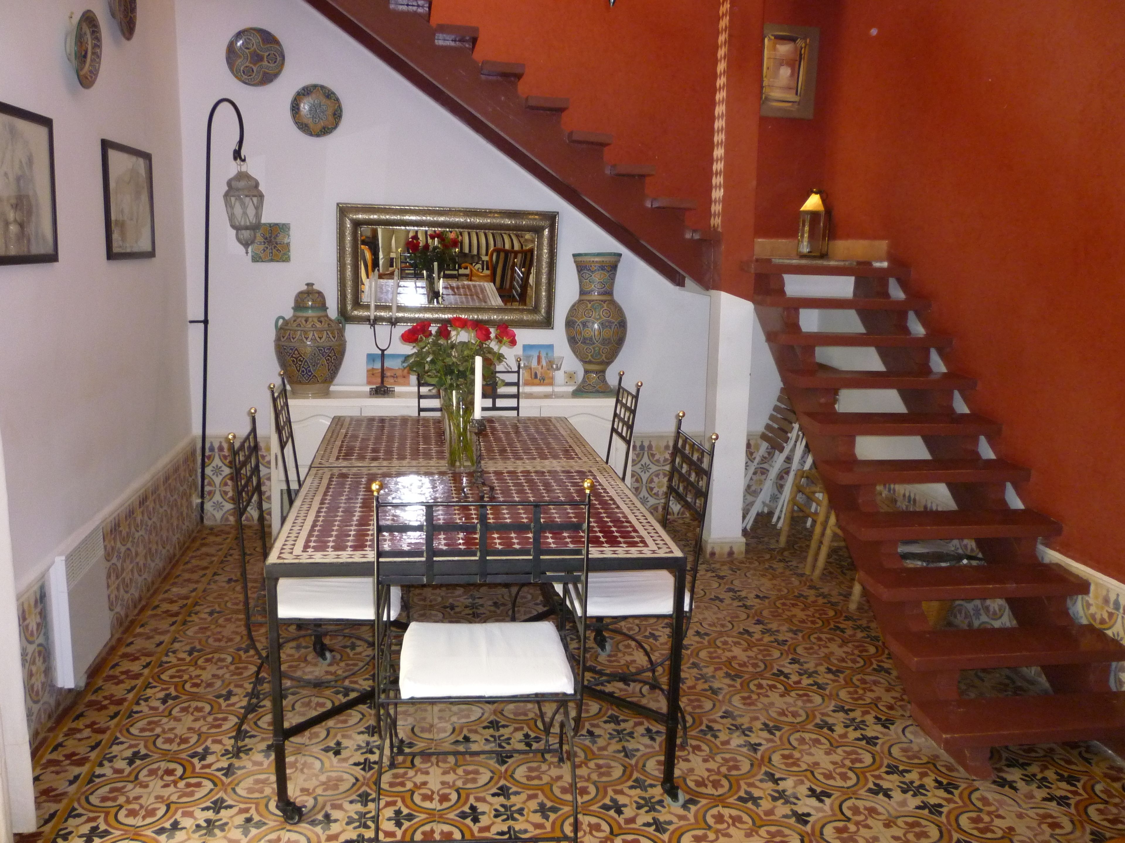 A dining area with a patterned table, chairs, and a staircase.